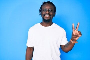 Young african american man with braids wearing casual white tshirt smiling with happy face winking at the camera doing victory sign. number two.