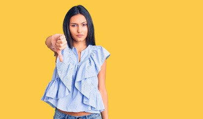 Young beautiful latin girl wearing casual clothes looking unhappy and angry showing rejection and negative with thumbs down gesture. bad expression.