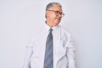 Senior grey-haired man wearing business clothes looking away to side with smile on face, natural expression. laughing confident.