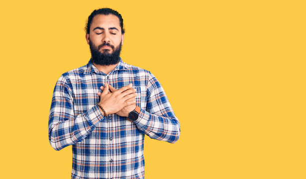 Young arab man wearing casual clothes smiling with hands on chest with closed eyes and grateful gesture on face. health concept.