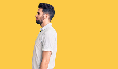 Young handsome man with beard wearing casual polo looking to side, relax profile pose with natural face with confident smile.