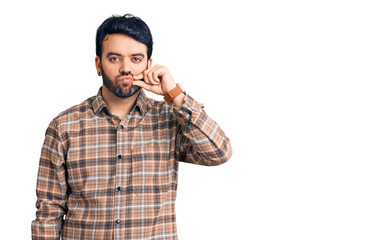 Young hispanic man wearing casual clothes mouth and lips shut as zip with fingers. secret and...