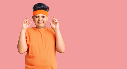 Little boy kid wearing sportswear gesturing finger crossed smiling with hope and eyes closed. luck and superstitious concept.