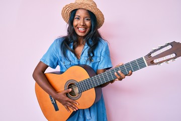 Young indian girl playing classical guitar smiling and laughing hard out loud because funny crazy joke.