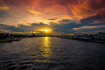 Naklejka premium The blurred abstract background of the evening sun shining on the river is naturally golden yellow, the beauty of the clouds and the weather conditions of the day.