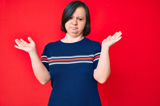 Brunette woman with down syndrome wearing casual clothes clueless and confused with open arms, no idea and doubtful face.