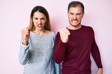 Beautiful couple wearing casual clothes angry and mad raising fist frustrated and furious while shouting with anger. rage and aggressive concept.
