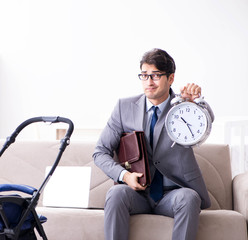 Businessman looking after newborn baby at home and teleworking