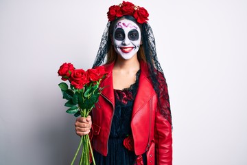 Woman wearing day of the dead costume holding roses looking positive and happy standing and smiling with a confident smile showing teeth