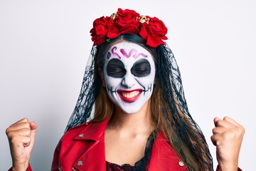 Fototapeta premium Woman wearing day of the dead costume over white very happy and excited doing winner gesture with arms raised, smiling and screaming for success. celebration concept.
