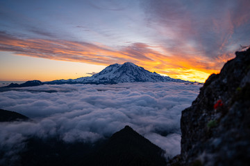 Panoramic view of Mount Rainier above the clouds during the sunrise with dramatic color in the sky