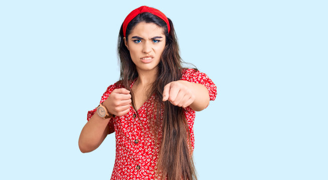 Brunette teenager girl wearing summer dress punching fist to fight, aggressive and angry attack, threat and violence