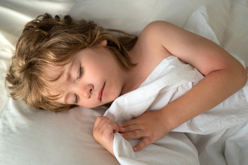 Sleeping kids lies in bed with eyes closed.