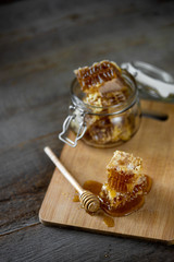 Pieces of fresh honeycomb with honey and glass jar on wooden background. Craft concept