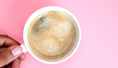 Hands with hot coffee in white cup.