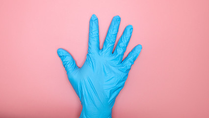 Doctor hand in Medical gloves blue on pink background.