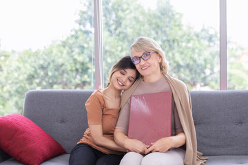 Obraz premium The adopted daughter bought insurance for her mother and caring smiling young woman embracing happy senior middle aged momat home spending time together.Unusual appearance, heredity concept.