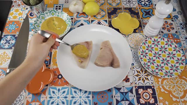 Female chef marinating swordfish at home, point of view shot