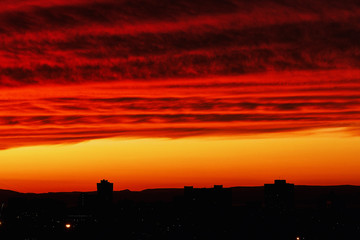 Juicy sunset sky in red-orange tones. A contrasting sunset over an evening city.