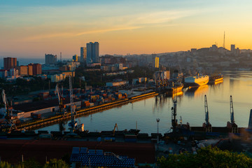 Summer, 2020 - Vladivostok, Russia - Dawn in Vladivostok. Aerial view of the Golden Horn Bay and the Commercial Sea Port. Cargo ships stand at the quay wall of the commercial port.