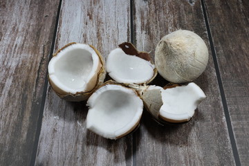 Cracked and half burned fresh coconut on the wooden plate. Famous traditional tropical fruit in Asia. Popular ingredients for Thai dessert.