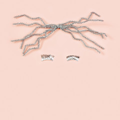 Woman face, minimal Christmas holiday flat lay.  Glossy hair and long eyelashes from silver foil decor