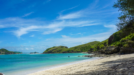 Fototapeta na wymiar Sandy beach in an island in Bali with emerald colored ocean blue sky