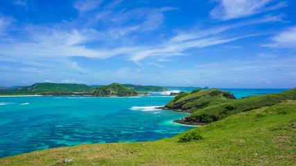 Obraz premium Green Hill at the Seashore in Bali with Emerald Colored Ocean, White Sand and Blue Sky