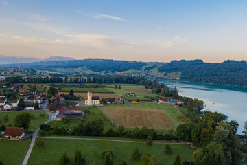 Fototapeta na wymiar village church and lake with alpine panorama
