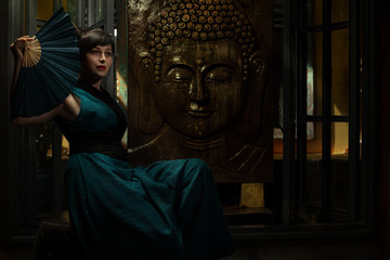 Fototapeta premium Geisha in dark turquoise kimono holding hand fan