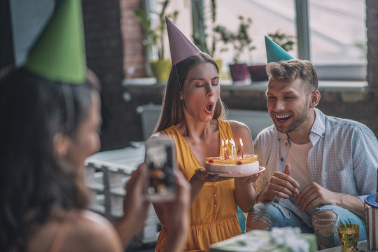 Woman taking picture of her friend blowing out candles