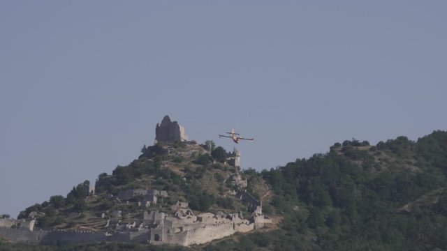 Canadair amphibious aircraft flying over a castle at low altitude