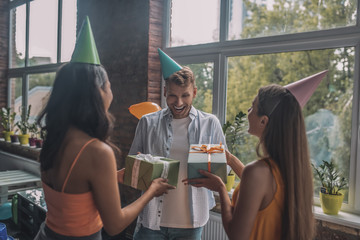 Joyful man receiving birthday gifts from his friends