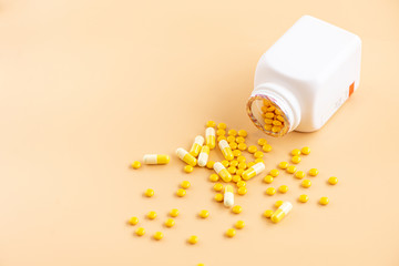 Composition of a medicine bottle, pills, and capsules on orange background.