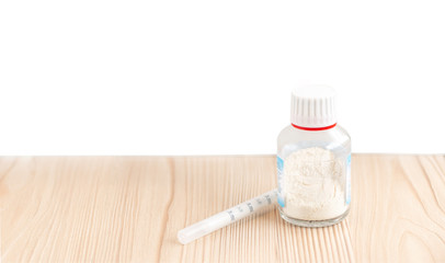 A bottle of dry powder bottle medicine with a syringe for kids on the white wooden background with the copy space.