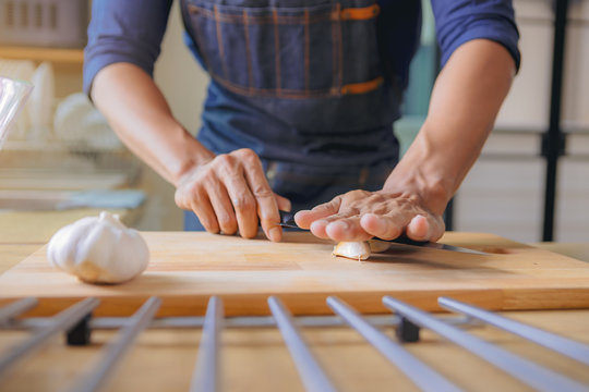 Chef using knife to smashing the fresh garlic, prepare for home cooking in modern kitchen.