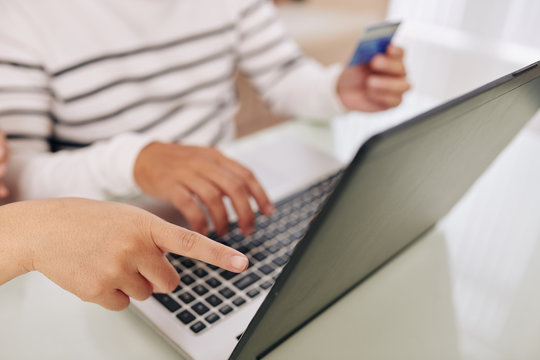 Close-up image of child pointing at laptop screen when mother paying for purchase with credit card