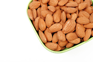 Group of almonds inside and outside bowl isolated on white.