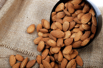 Group of almonds inside and outside bowl isolated on white.