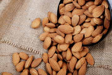 Group of almonds inside and outside bowl isolated on white.