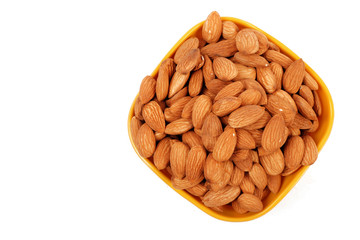 Group of almonds inside and outside bowl isolated on white.