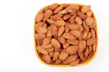 Group of almonds inside and outside bowl isolated on white.
