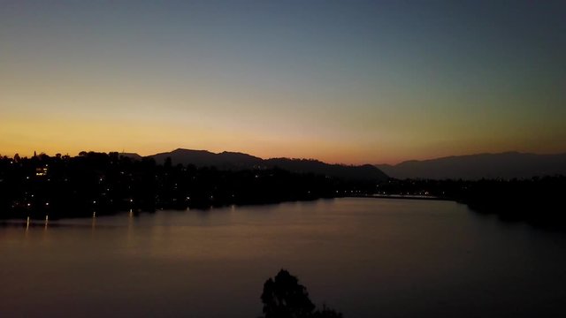 Aerial rising shot of urban lake in Los Angeles during sunset. 4K