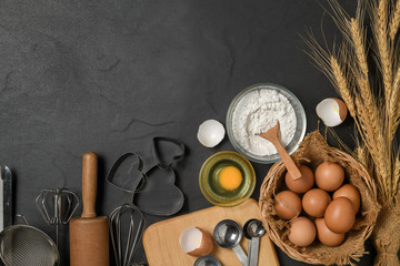 fresh eggs and cake flour  with kitchen utensils for pastries on black table,