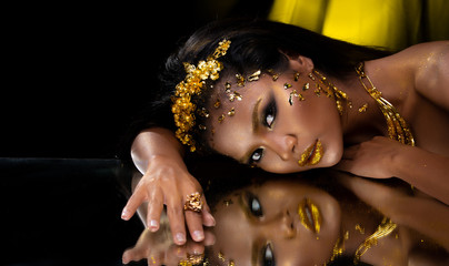 woman apply fashion gold leaf on face head and reflect mirror