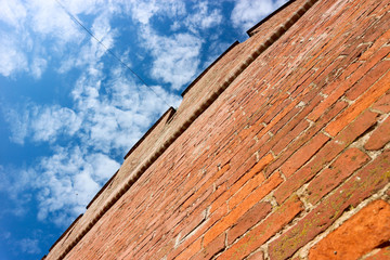 Fototapeta na wymiar red brick fortress wall with blue cloudy sky