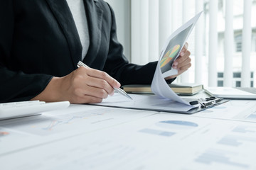 The hands of a male businesswoman are analyzing and calculating the annual income and expenses in a...