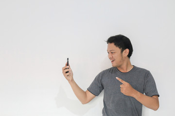 Wow face and feeling happy of Young Asian man in grey t-shirt get surprised on the smartphone.
