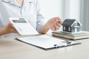 Fototapeta premium Agents working in real estate investment There a house model Hold a pen and a calculator and home lease contract And home insurance According to the insurance contract Home purchase approved.