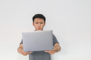 Wow face of Your Asian man shocked what he see in the laptop on isolated grey background.